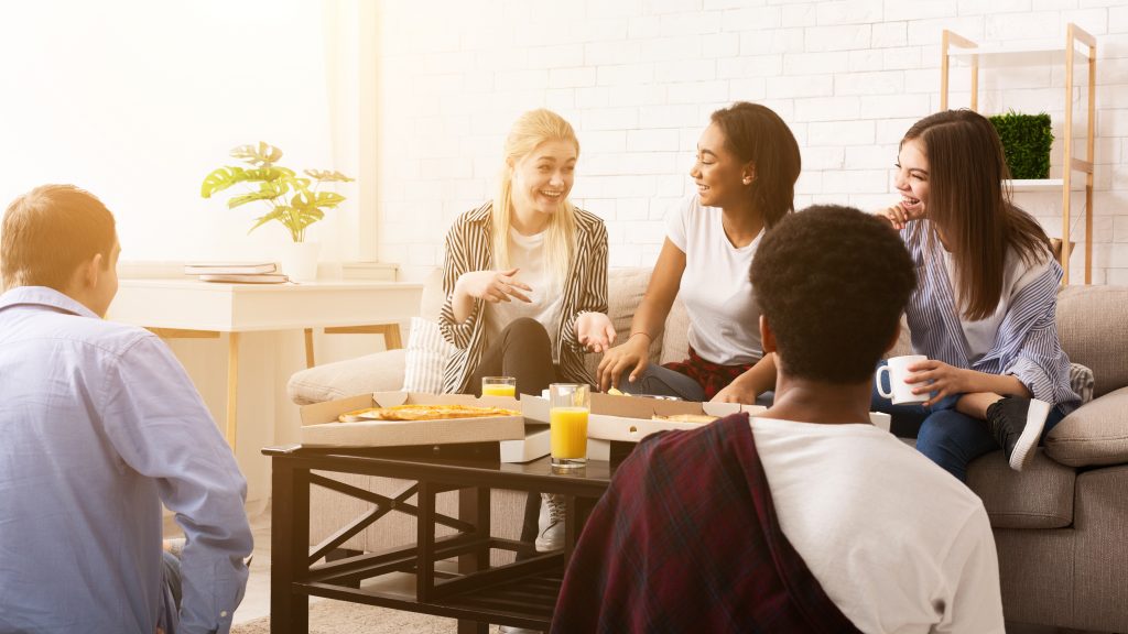 Amigos hablando y tomando pizzas durante visita exprés a pisos de estudiantes