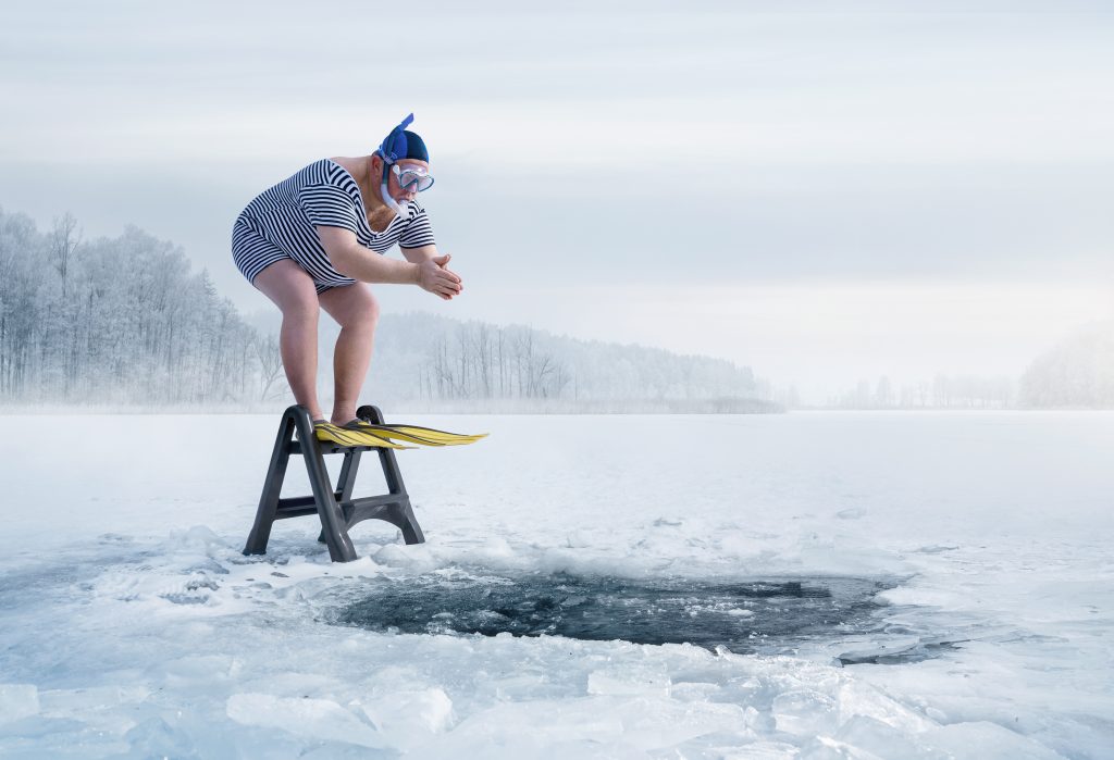 Nadador a punto de saltar en el agujero de hielo en un lago. Practicando deporte de invierno.